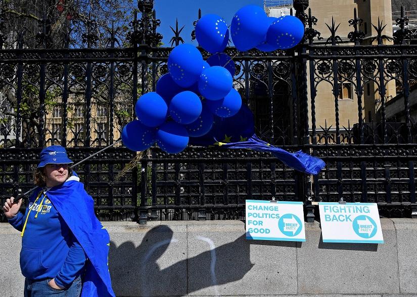 An anti-Brexit protester stands next to Brexit Party campaign placards outside of the Houses of Parliament in London, Britain, May 16, 2019. REUTERS