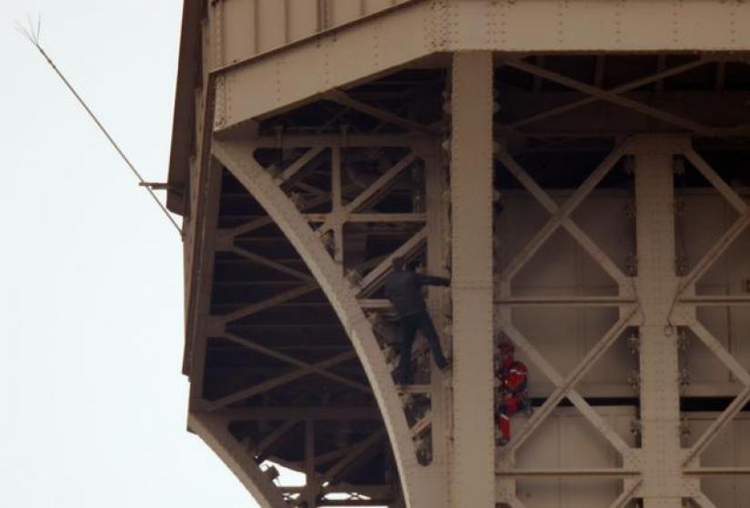 An unidentified man climbs the Eiffel Tower, which had to be evacuated, next to a Paris fire brigade specialist in Paris, France, May 20, 2019. REUTERS