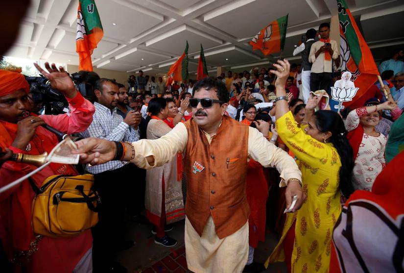 A supporter of Bharatiya Janata Party (BJP) gives money to musicians during celebrations after learning of initial poll results outside the party office in Gandhinagar, India, May 23, 2019. REUTERS