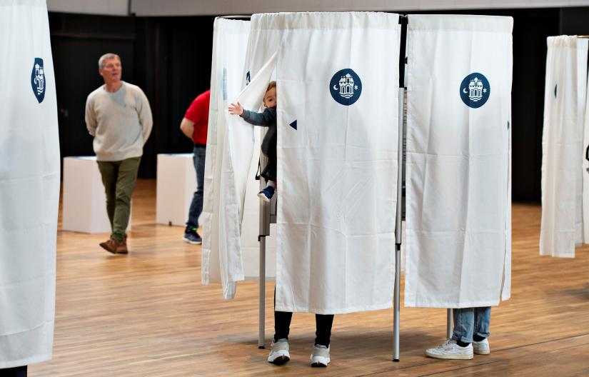 A child peeks through the curtain from inside a voting booth during the European Parliament election at the Aalborghallen arena, in Aalborg, Denmark May 26, 2019. Ritzau Scanpix/Henning Bagger via REUTERS