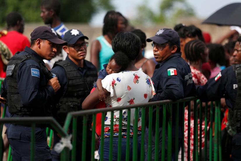 Federal police officers talk with an African migrant as she waits to be admitted outside of Siglo XXI migration facility in Tapachula, Mexico, June 12, 2019. REUTERS
