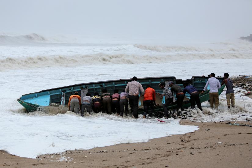 Fishermen move a fishing boat to a safer place along the shore ahead of Cyclone Vayu in Veraval, India, June 13, 2019. REUTERS