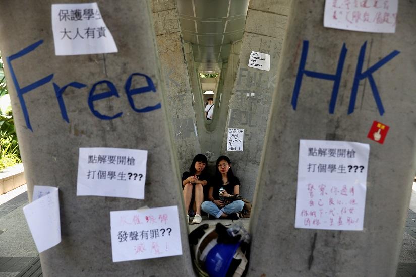 People sit next to posters and signs placed following protests against the proposed extradition bill, in Hong Kong, China June 14, 2019. REUTERS