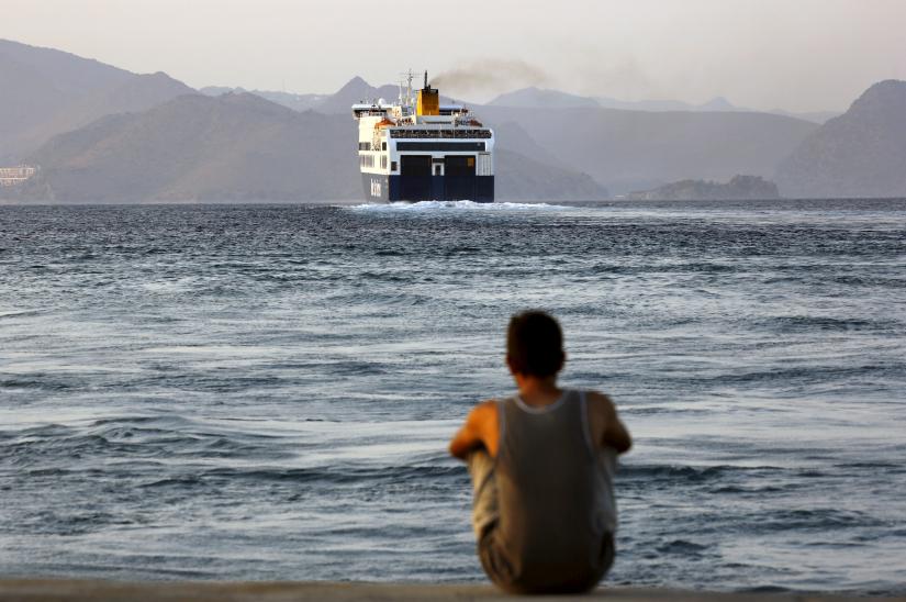 A Bangladeshi migrant, pending temporary documentation, watches from the port of Kos, Greece, a ferry bound for the port of Piraeus near Athens August 10, 2015.
