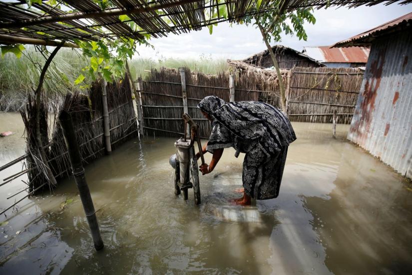 A woman collects drinking water from a flooded tube well in Gaibandha, Bangladesh August 19, 2017. REUTERS/File Photo