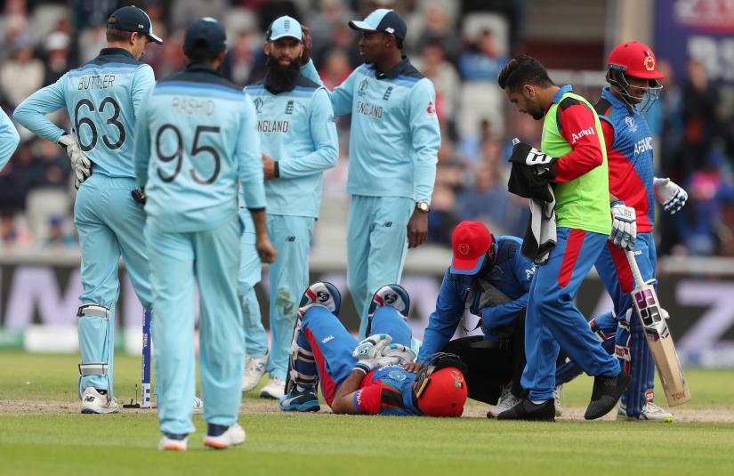 ICC Cricket World Cup - England v Afghanistan - Old Trafford, Manchester, Britain - June 18, 2019 Afghanistan`s Hashmatullah Shahidi is checked on by a physio after being hit on the head off a bowl from England`s Mark Wood Action Images via Reuters