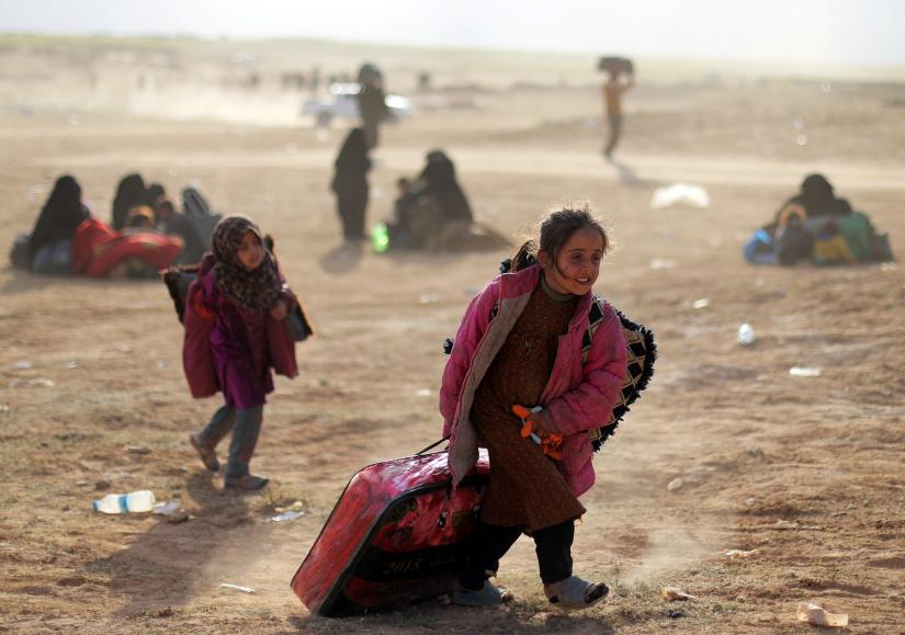 A girl walks with her belongings near Baghouz, Deir Al Zor province, Syria March 5, 2019. REUTERS