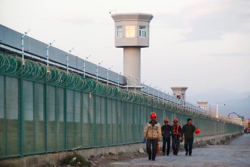 Workers walk by the perimeter fence of what is officially known as a vocational skills education centre in Dabancheng in Xinjiang Uighur Autonomous Region, China September 4, 2018. REUTERS/File Photo