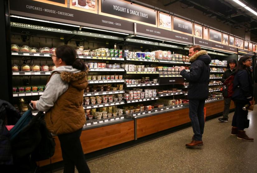 Customers browse the yogurt and deli sections in the new Amazon Go store at Amazon`s Seattle headquarters in Seattle, Washington, US, Jan 29, 2018. REUTERS/File Photo
