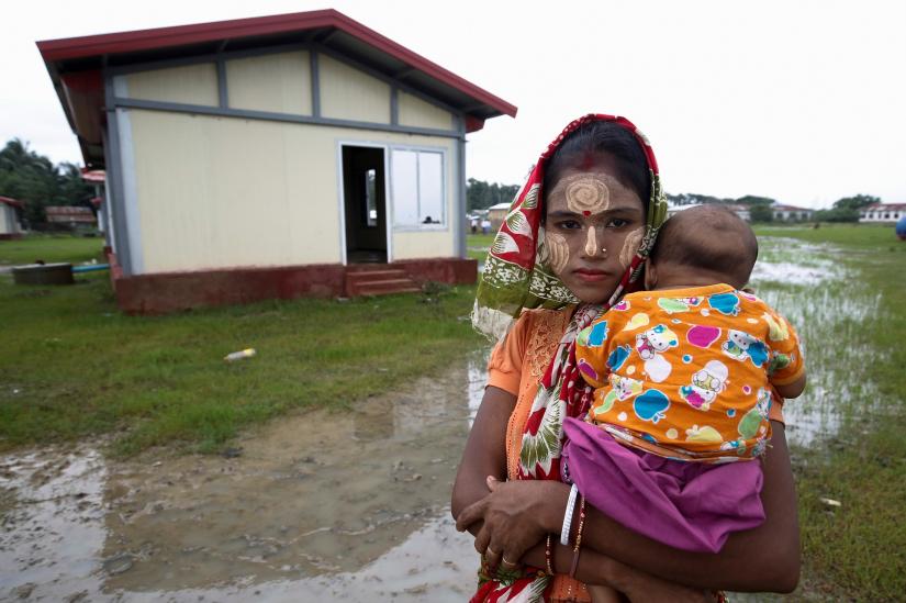Displaced Hindu woman with a child is pictured next to a new house, built by Indian and Myanmar governments friendship project, in Maungdaw, Rakhine, Myanmar, July 9, 2019. REUTERS