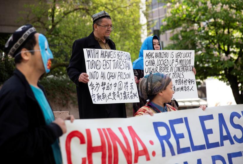 Parhat Kasim and his wife Dilibair Yusuf hold signs protesting China`s treatment of Uighur people in the Xinjiang region during a court appearance by Huawei`s Financial Chief Meng Wanzhou, outside of British Columbia Supreme Court building in Vancouver, British Columbia, Canada, May 8, 2019. REUTERS/File Photo