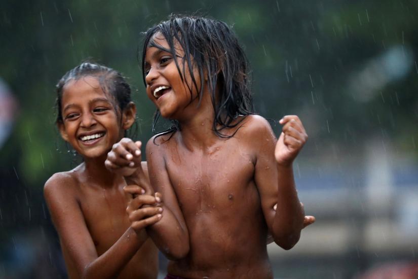 Children smile as they enjoy heavy rain in Dhaka, Bangladesh, July 13, 2019. REUTERS