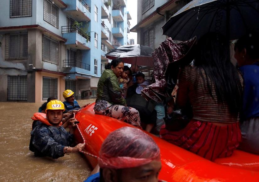 A woman carrying a child is moved by rescue workers towards dry ground from a flooded colony in Kathmandu, Nepal July 12, 2019. REUTERS