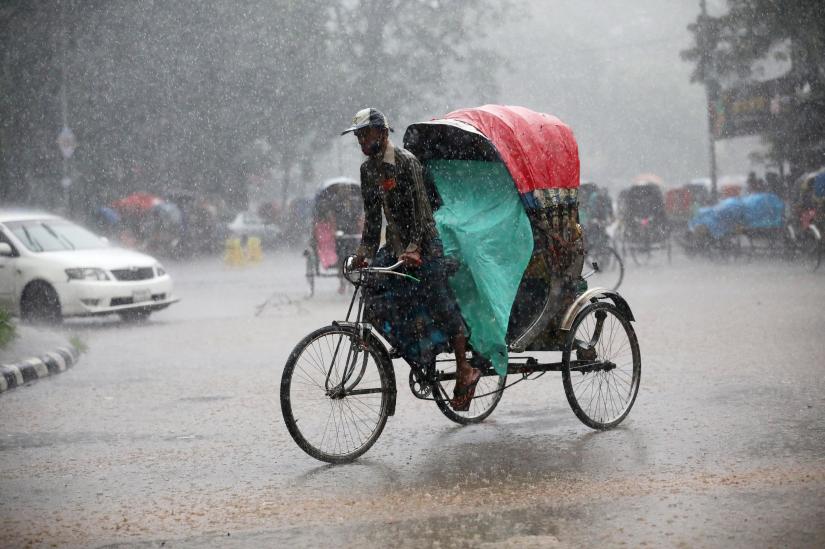 A man rides a rickshaw during heavy rain in Dhaka, Bangladesh, July 13, 2019. REUTERS