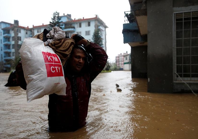 A man carrying his belongings walks towards dry ground from a flooded colony in Kathmandu, Nepal July 12, 2019. REUTERS