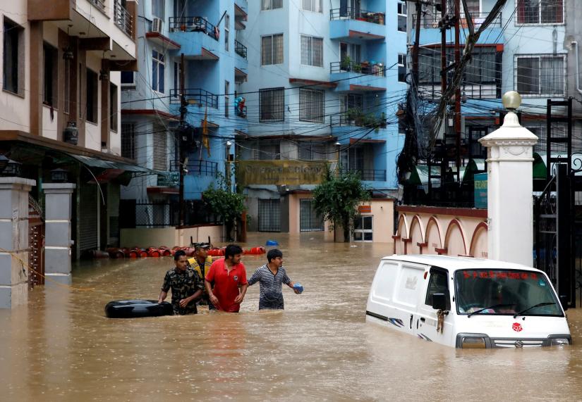 Residents walk towards the dry ground from a flooded colony in Kathmandu, Nepal July 12, 2019. REUTERS
