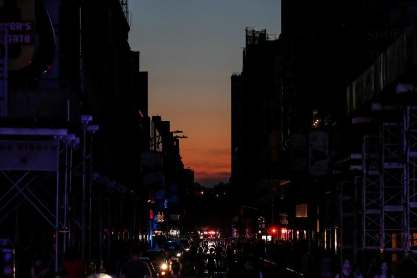 People walk along a dark street near Times Square area, as a blackout affects buildings and traffic during widespread power outages in the Manhattan borough of New York, U.S, July 13, 2019. REUTERS