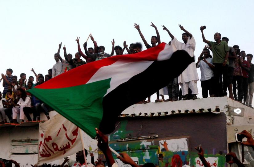 Sudanese people chant slogans and wave their national flag as they celebrate, after Sudan`s ruling military council and a coalition of opposition and protest groups reached an agreement to share power during a transition period leading to elections, along the streets of Khartoum, Sudan, Jul 5, 2019. REUTERS/File Photo