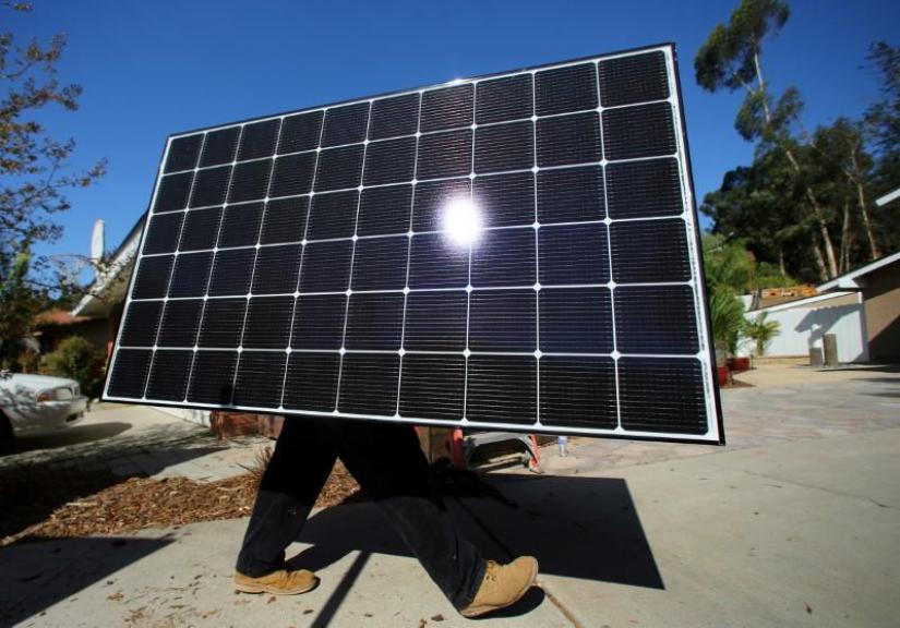 A solar installer carries a solar panel during an installation at a residential home in Scripps Ranch, San Diego, California, U.S. October 14, 2016. Reuters