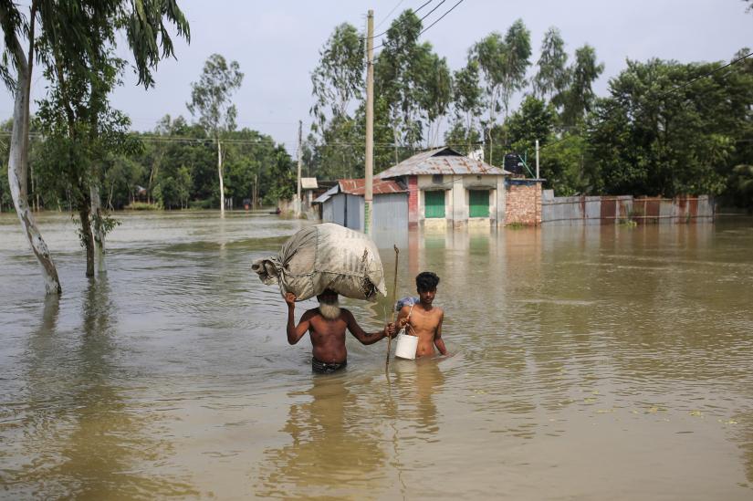 People move along a flooded area with their belongings in Gaibandha, Bangladesh, July 19, 2019. REUTERS