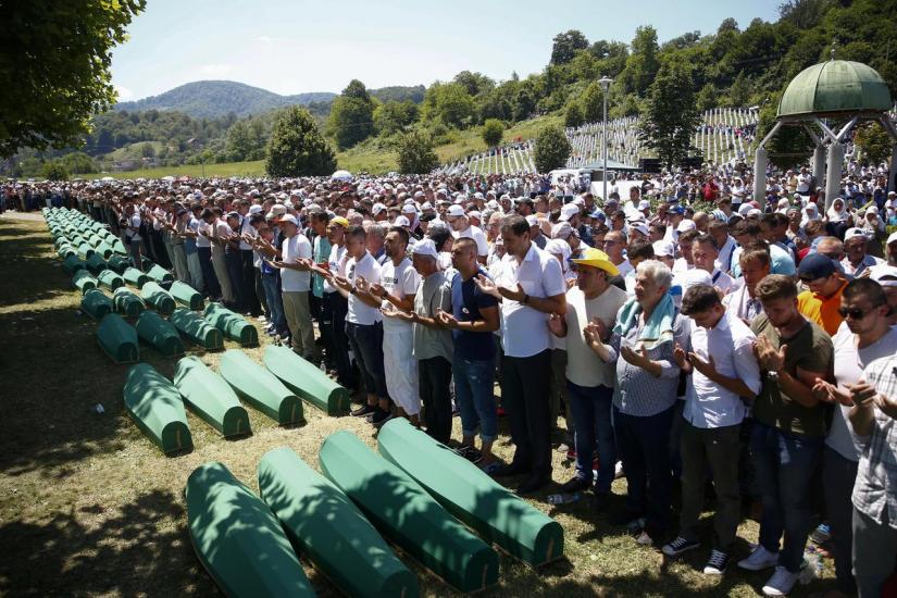 People pray near coffins of their relatives, who are newly identified victims of the 1995 Srebrenica massacre, which are lined up for a joint burial in Potocari near Srebrenica, Bosnia and Herzegovina, Jul 11, 2017. REUTERS/File Photo