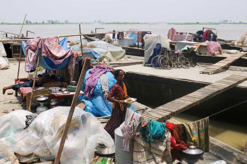 Woman is seen next to temporary shelters on the embankment of the river Brahmaputra in the flooded area in Gaibandha, Bangladesh, July 19, 2019. REUTERS