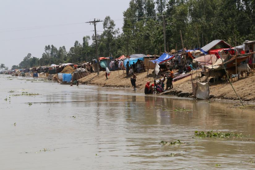 People are seen next to temporary shelters on the embankment of the river Brahmaputra in the flooded area in Gaibandha, Bangladesh, July 19, 2019. REUTERS