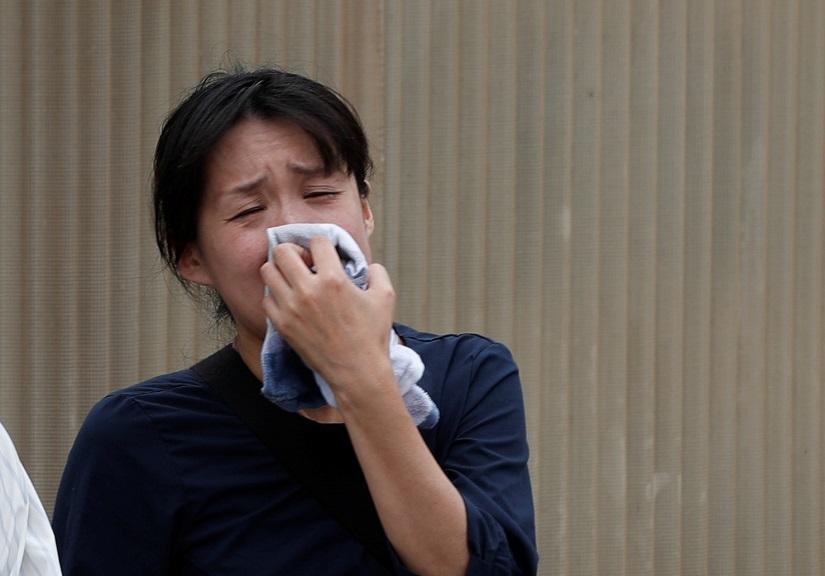 A woman cries as she looks at the torched Kyoto Animation building in Kyoto, Japan, July 20, 2019. REUTERS