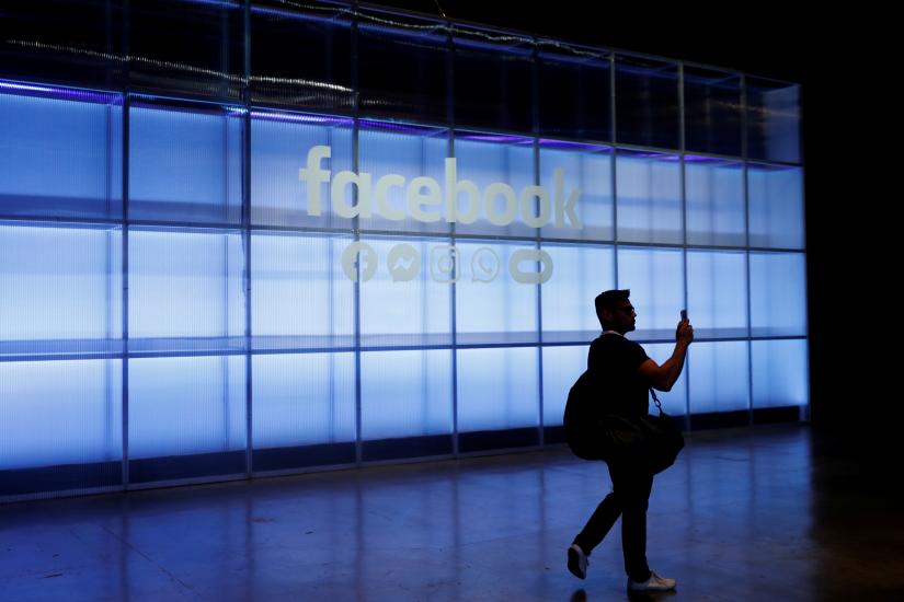 An attendee takes a photograph of a sign during Facebook Inc`s F8 developers conference in San Jose, California, US, Apr 30, 2019. REUTERS/File Photo