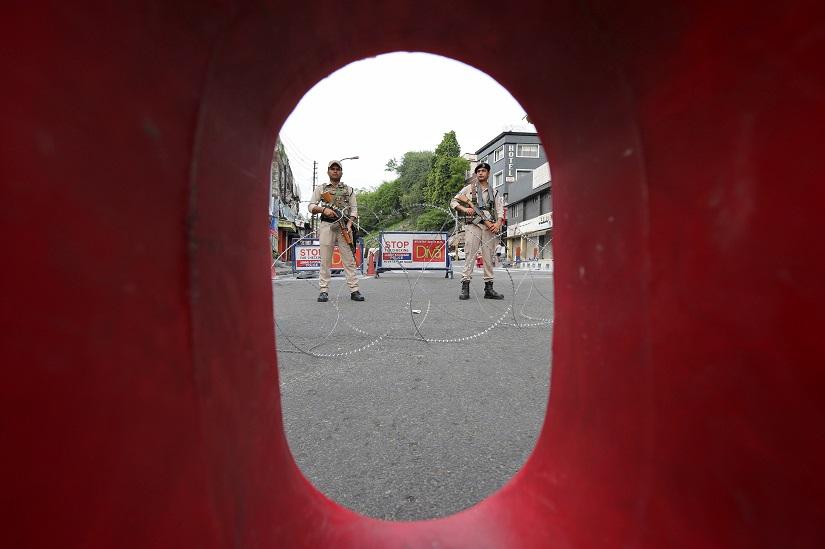 Indian security personnel stands guard behind a roadblock along a deserted street during restrictions in Jammu, August 5, 2019. REUTERS