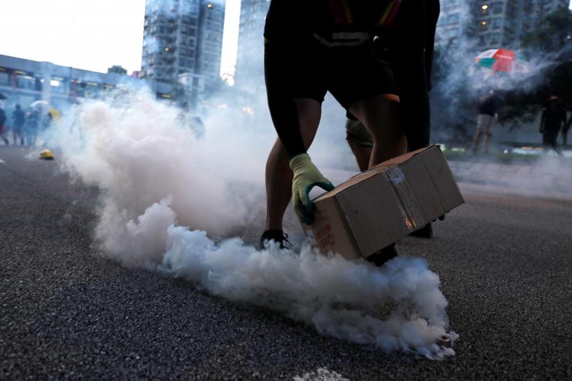 A protester covers a tear gas canister fired by the police during a demonstration in support of the city-wide strike and to call for democratic reforms at Tai Po residential area in Hong Kong, China, August 5, 2019. REUTERS