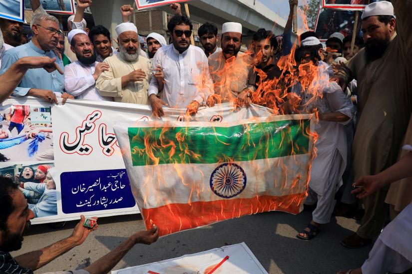 People chant slogans as they set on fire the representation of India`s flag during a rally to express solidarity with the people of Kashmir, in Peshawar, Pakistan August 6, 2019. REUTERS
