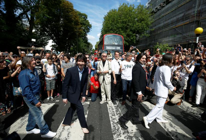 People take pictures as the Beatles cover band members walk on the zebra crossing on Abbey Road in London, Britain August 8, 2019. REUTERS