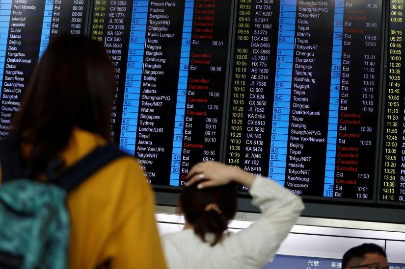 Passengers react as they look at the flight information board as the airport reopened a day after flights were halted due to a protest, at Hong Kong International Airport, China August 13, 2019. REUTERS