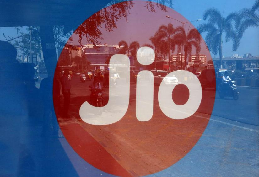 FILE PHOTO: Commuters` reflections are seen on an advertisement for Reliance Industries` Jio telecoms business at a bus stop in Mumbai, India, February 21, 2017. REUTERS/File Photo
