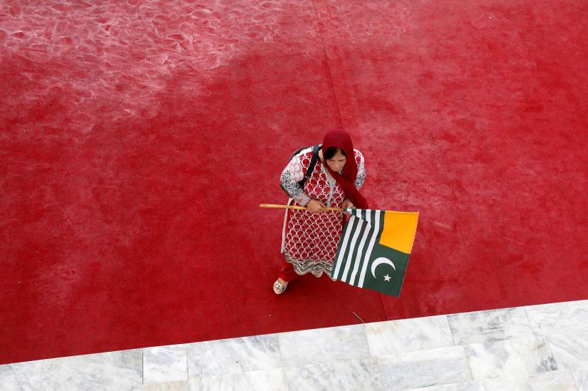 A woman walks with a Kashmir`s flag to express solidarity with the people of Kashmir, during a ceremony to celebrate Pakistan`s 72nd Independence Day at the Mausoleum of Muhammad Ali Jinnah in Karachi, Pakistan August 14, 2019. REUTERS
