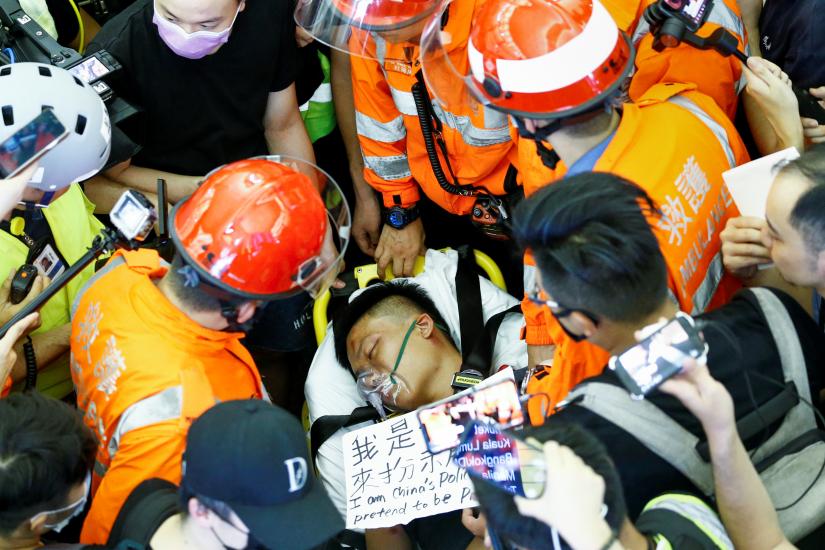 Medics attempt to remove an injured man, who some anti-government protesters said was an undercover police officer from mainland China, at the airport in Hong Kong, China August 13, 2019. REUTERS