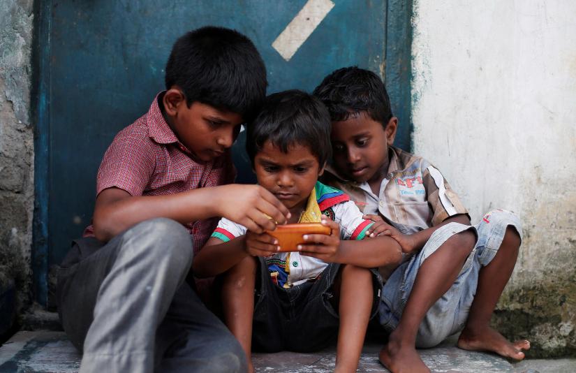 Children play a game on a mobile phone at slum area in New Delhi, India July 4, 2017. REUTERS