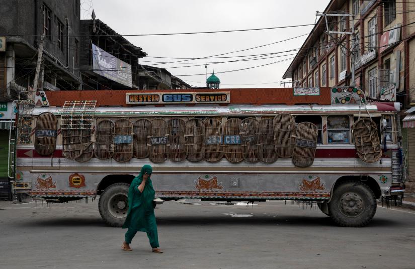 FILE PHOTO: A Kashmiri woman walks past a bus used as a road block by Indian security personnel during restrictions after the scrapping of the special constitutional status for Kashmir by the government, in Srinagar, August 11, 2019. REUTERS