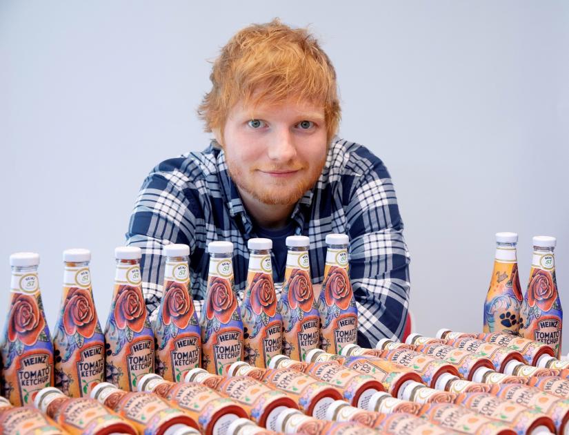 Ed Sheeran poses with bottles of Heinz Tomato Ketchup based on his tattoos in London, Britain May 20, 2019, in this handout photo. Heinz/Handout via REUTERS
