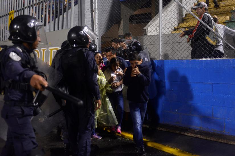Spectators react from tear gas after three people died in riots before a soccer match when the fans attacked a bus carrying one of the teams, at the National Stadium in Tegucigalpa, Honduras August 17, 2019. REUTERS