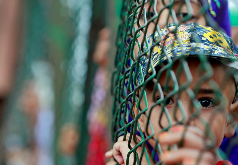 Kashmiri child looks from behind a fence at a protest site after Friday prayers during restrictions after the Indian government scrapped the special constitutional status for Kashmir, in Srinagar, August 16, 2019. REUTERS