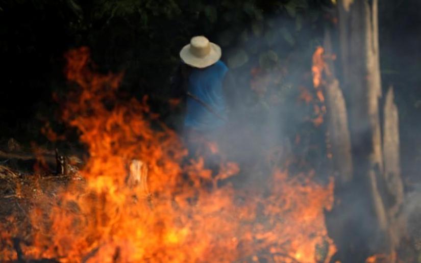 A man works in a burning tract of Amazon jungle as it is being cleared by loggers and farmers in Iranduba, Amazonas state, Brazil August 20, 2019. REUTERS