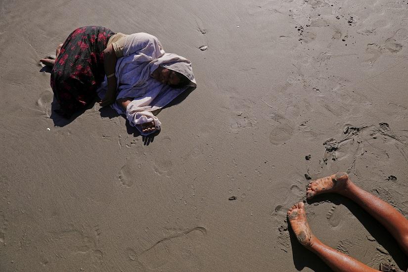 FILE PHOTO: Rohingya refugees collapse from exhaustion after they arrive by a small wooden boat from Myanmar to the shore of Shah Porir Dwip, in Teknaf, near Cox`s Bazar in Bangladesh, Oct 1, 2017. REUTERS