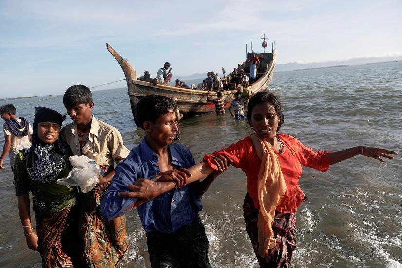 FILE PHOTO: Shakira, a 22 year old Rohingya is helped as refugees arrive by a wooden boat from Myanmar to the shore of Shah Porir Dwip, in Teknaf, near Cox`s Bazar in Bangladesh, Oct 1, 2017. REUTERS