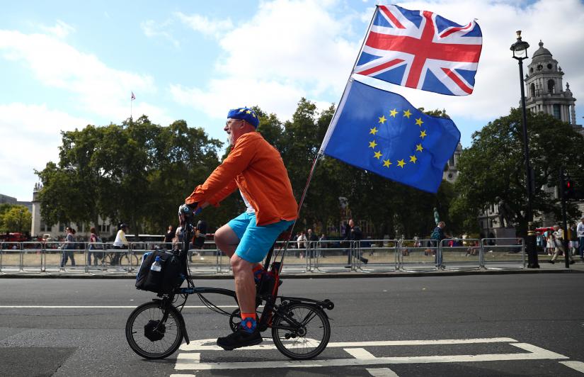 An anti-Brexit protestor rides a bicycle with Union Jack flag and European Union flag attached to it, outside the Houses of the Parliament in London, Britain, September 3, 2019. REUTERS