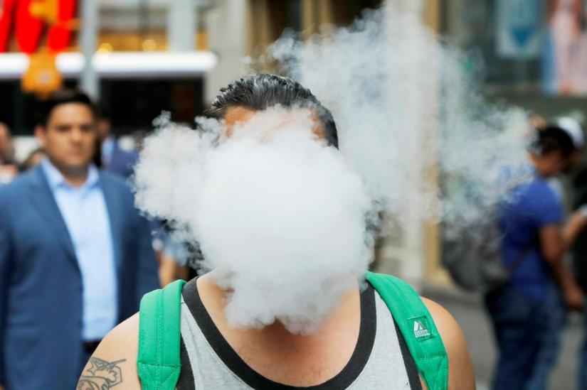 FILE PHOTO: A man uses a vape as he walks on Broadway in New York City, US, Sept 9, 2019. REUTERS