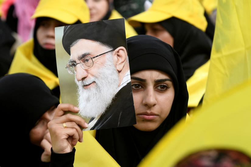 FILE PHOTO: A woman carries a picture of Iran`s Supreme Leader Ayatollah Ali Khamenei as she watches Lebanon`s Hezbollah leader Sayyed Hassan Nasrallah appear on a screen during a live broadcast to speak to his supporters at an event marking Resistance and Liberation Day in the Bekaa Valley, Lebanon, May 25, 2017. REUTERS