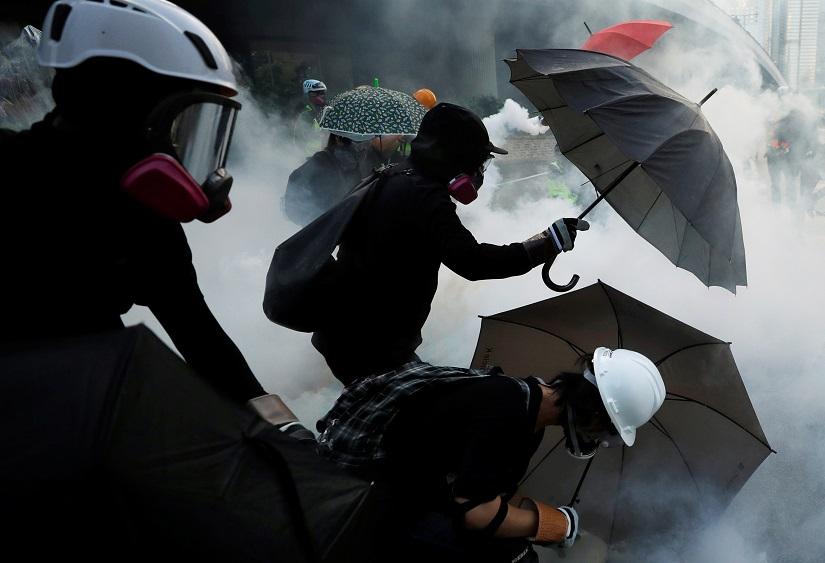 Anti-government protesters protect themselves with umbrellas among tear gas during a demonstration near Central Government Complex in Hong Kong, China, Sept 15, 2019. REUTERS