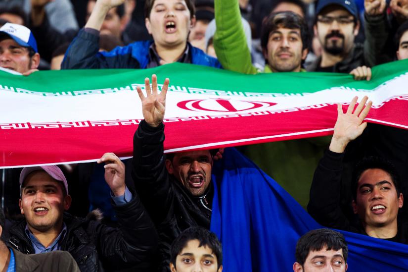 FILE PHOTO: Fans of Iran`s Esteghlal cheer as they hold their national flag during their AFC Champions League soccer match playoff against Saudi Arabia`s Al Ittifaq, in Tehran February 18, 2012. REUTERS